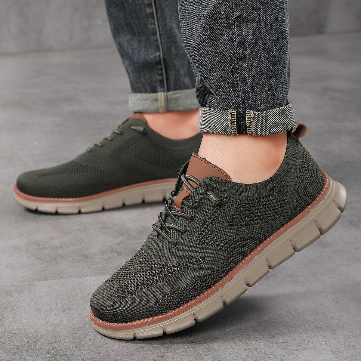 Dark Green sneakers with brown soles worn with rolled-up jeans on a gray surface