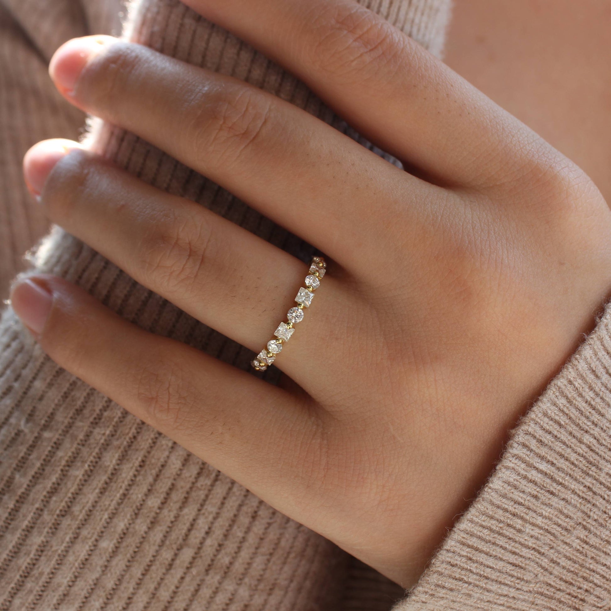 Delicate alternating moissanite eternity band worn on finger in soft natural light