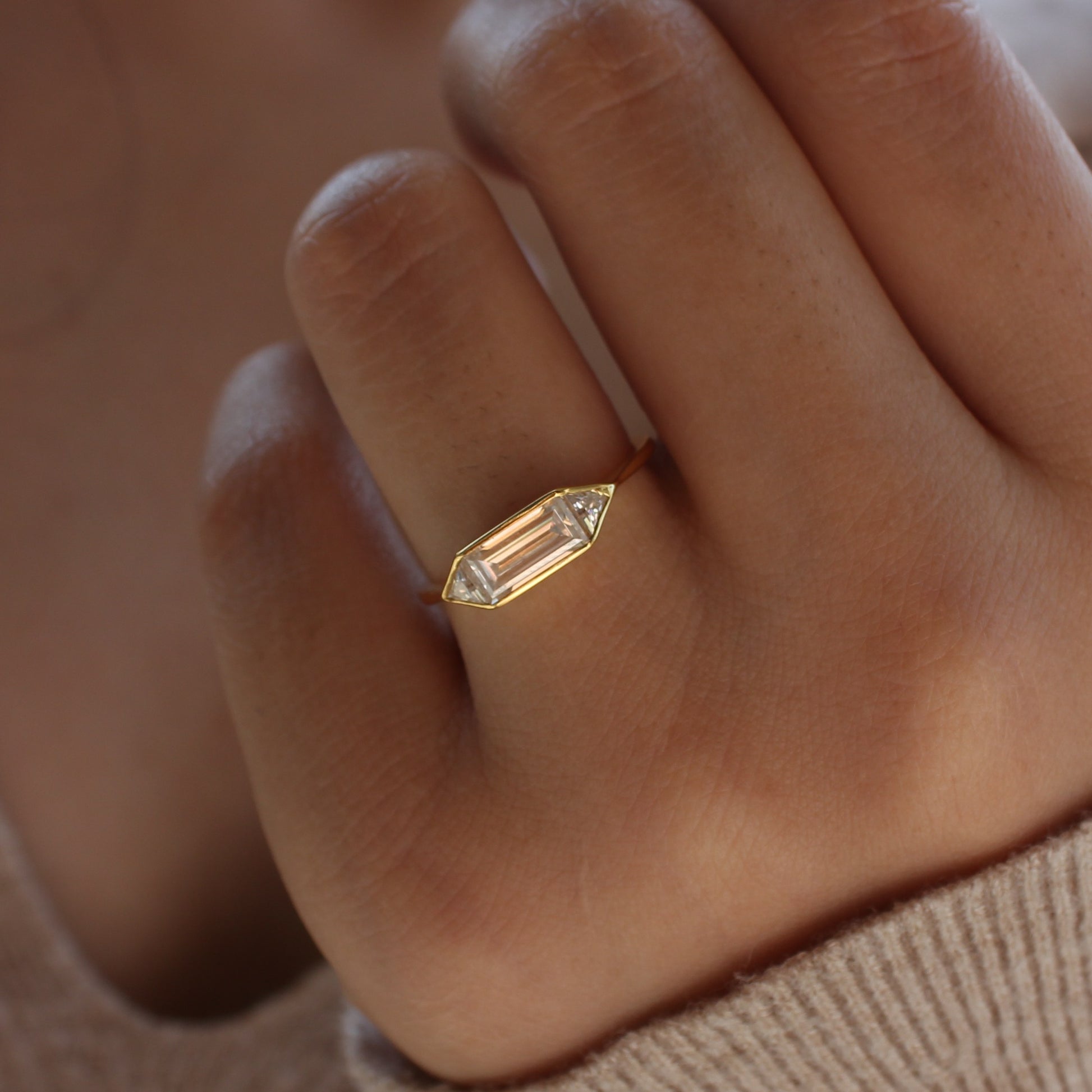 Delicate emerald bezel moissanite ring on hand, gold plated sterling silver