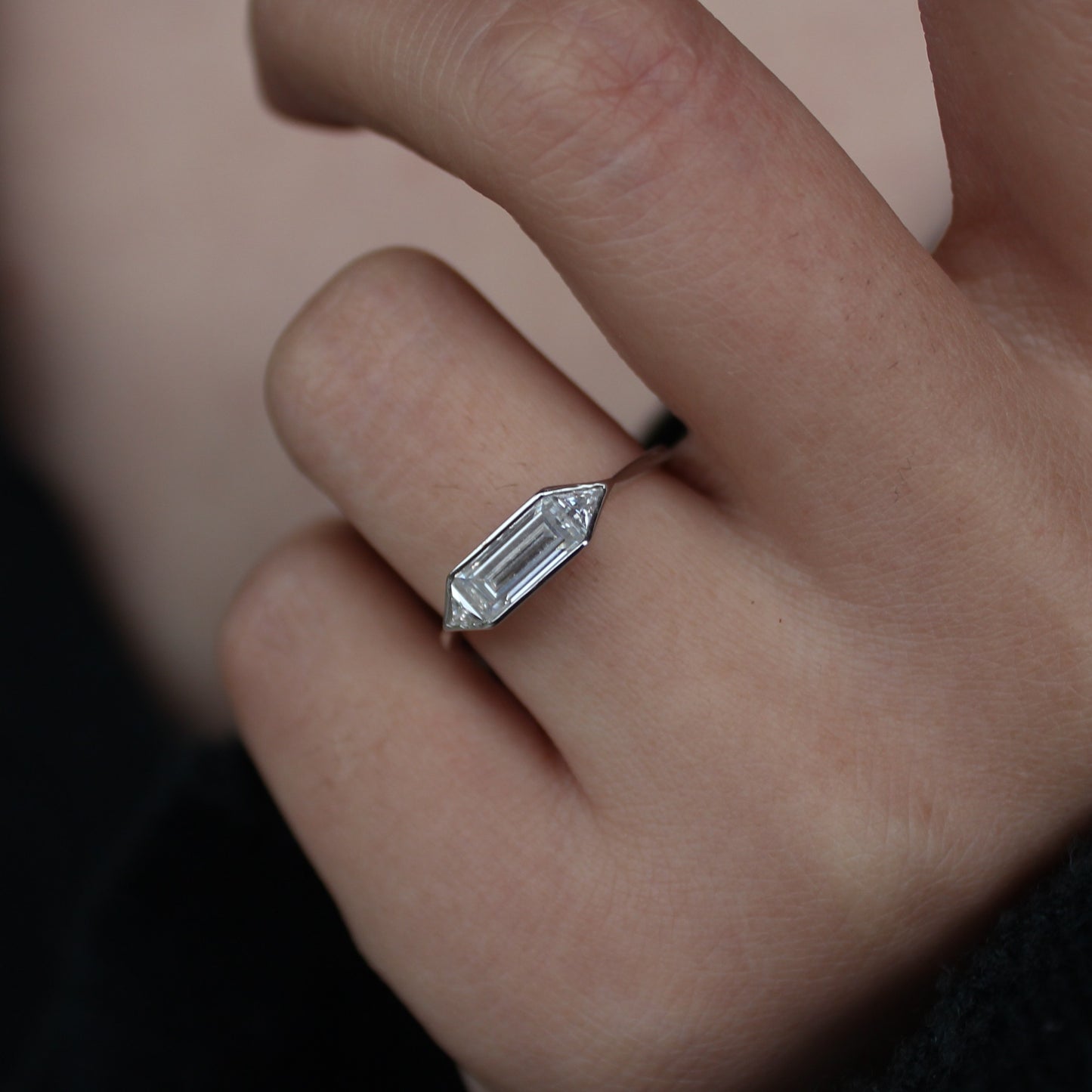 Emerald cut moissanite bezel ring worn on hand, clean minimalist look