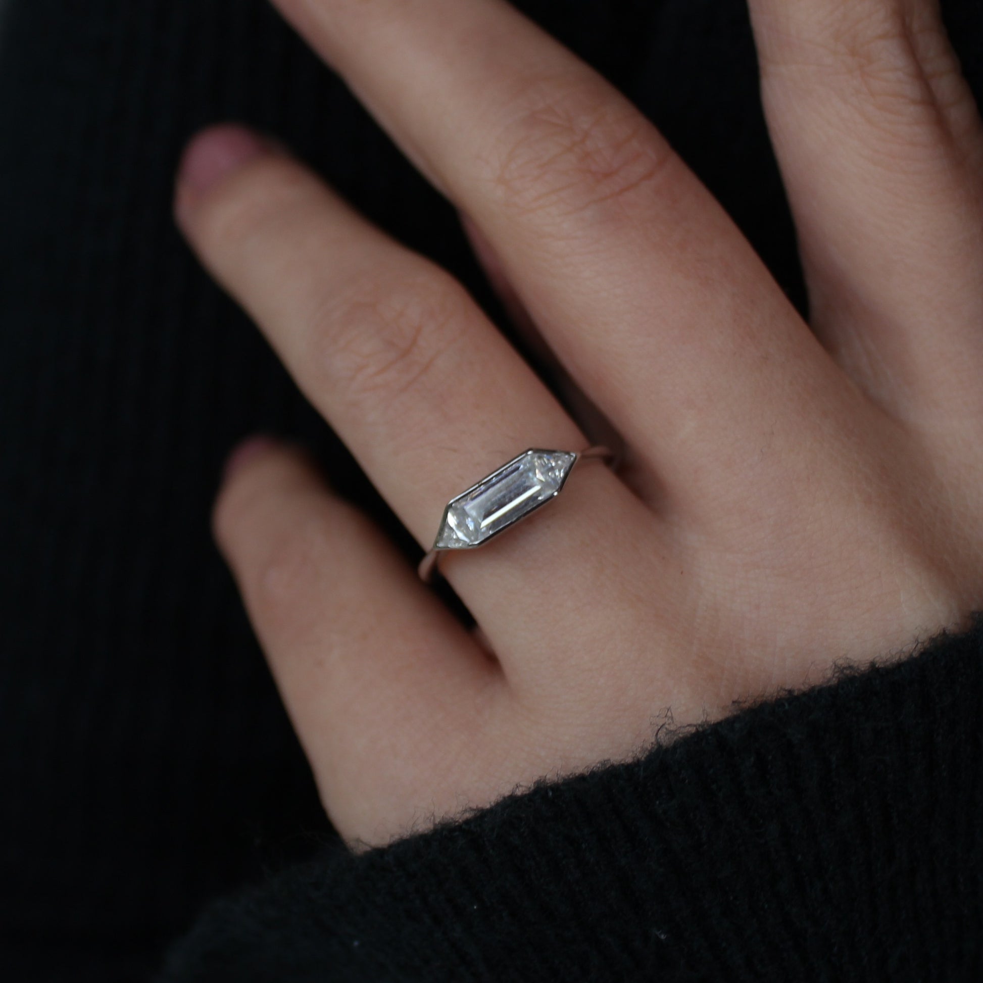 Minimal emerald moissanite bezel ring worn on finger, modern style