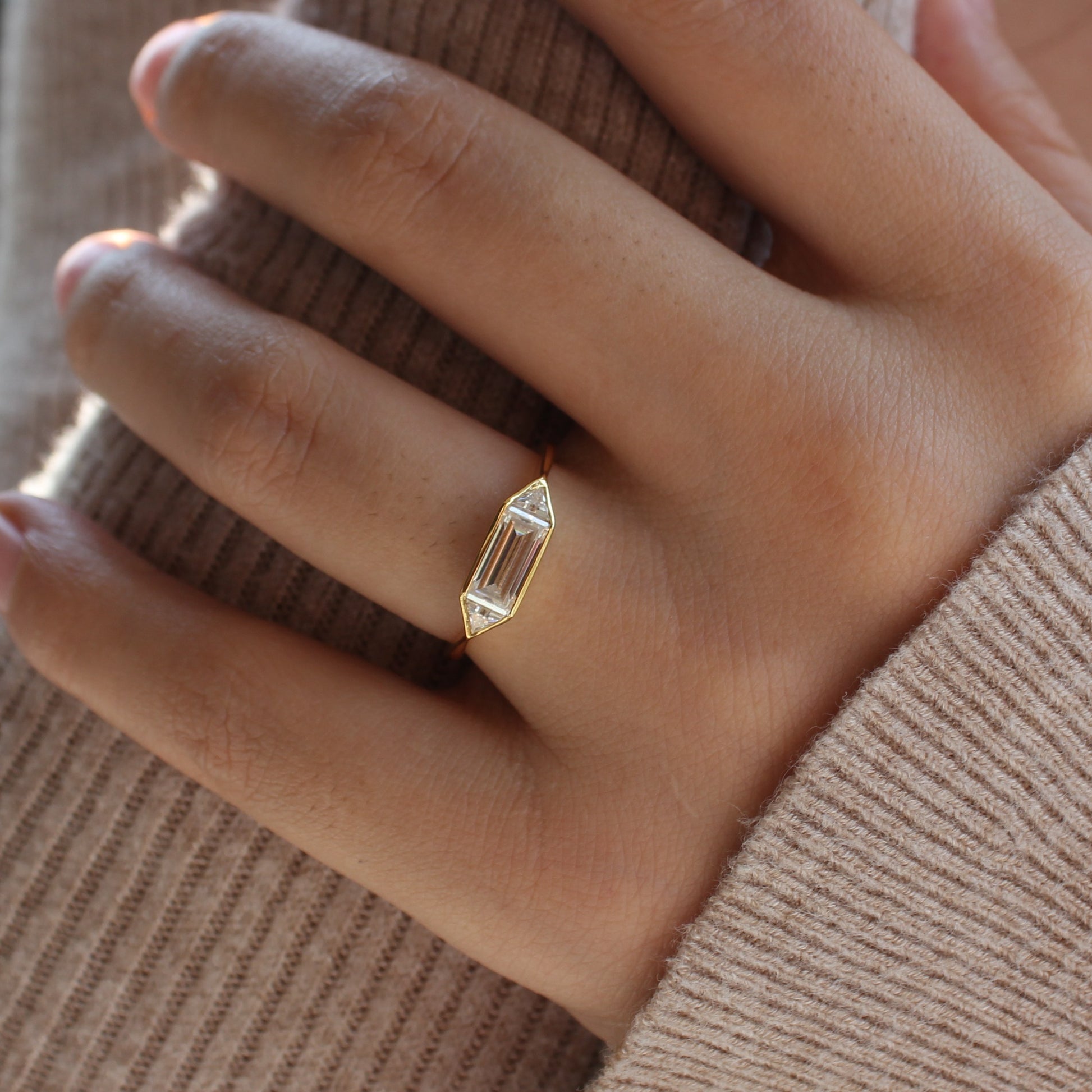 Slim emerald cut moissanite ring worn on hand, bezel setting