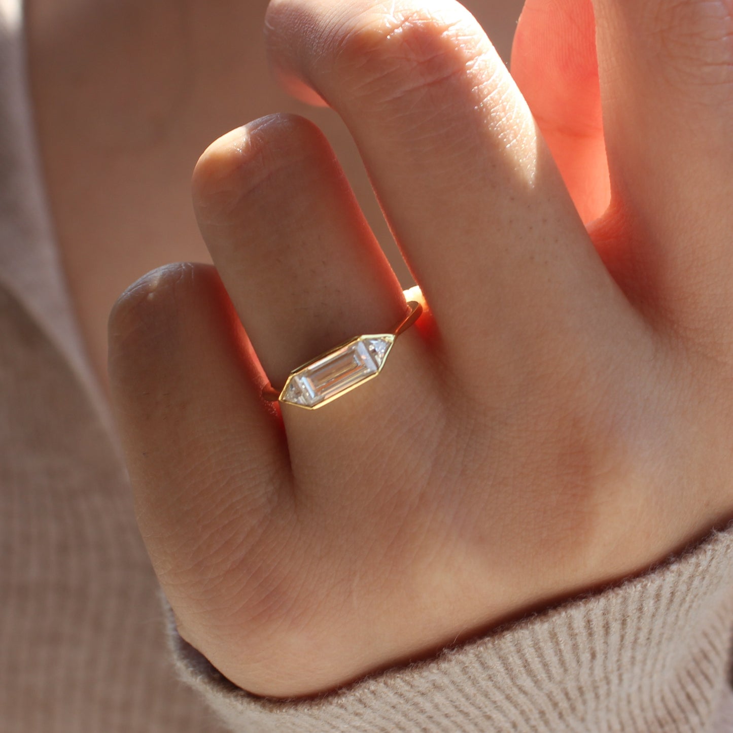 Emerald cut moissanite bezel ring worn on hand, 18K gold plated sterling silver