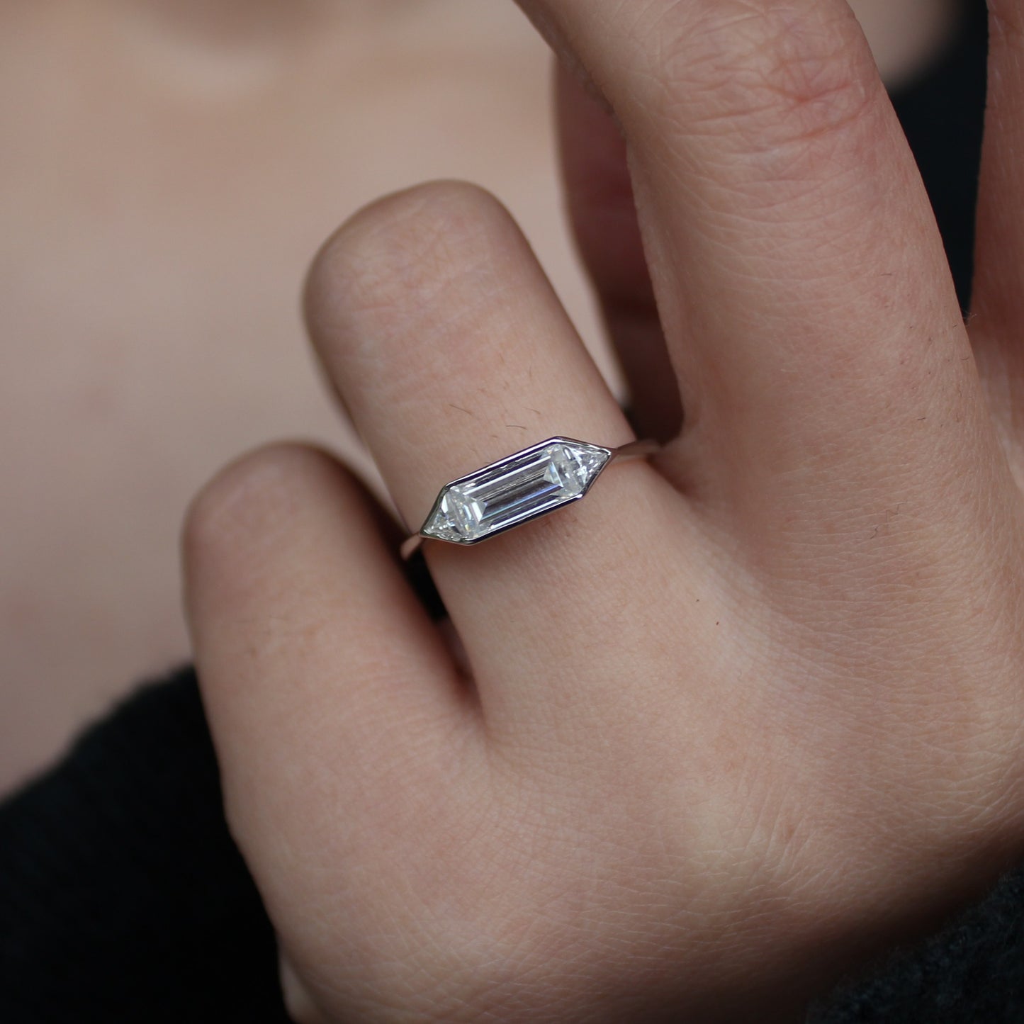 Emerald bezel moissanite ring worn on hand in white gold tone