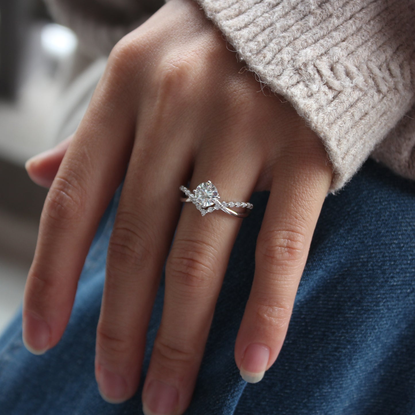 Minimalist curved moissanite ring worn on finger, white gold tone finish