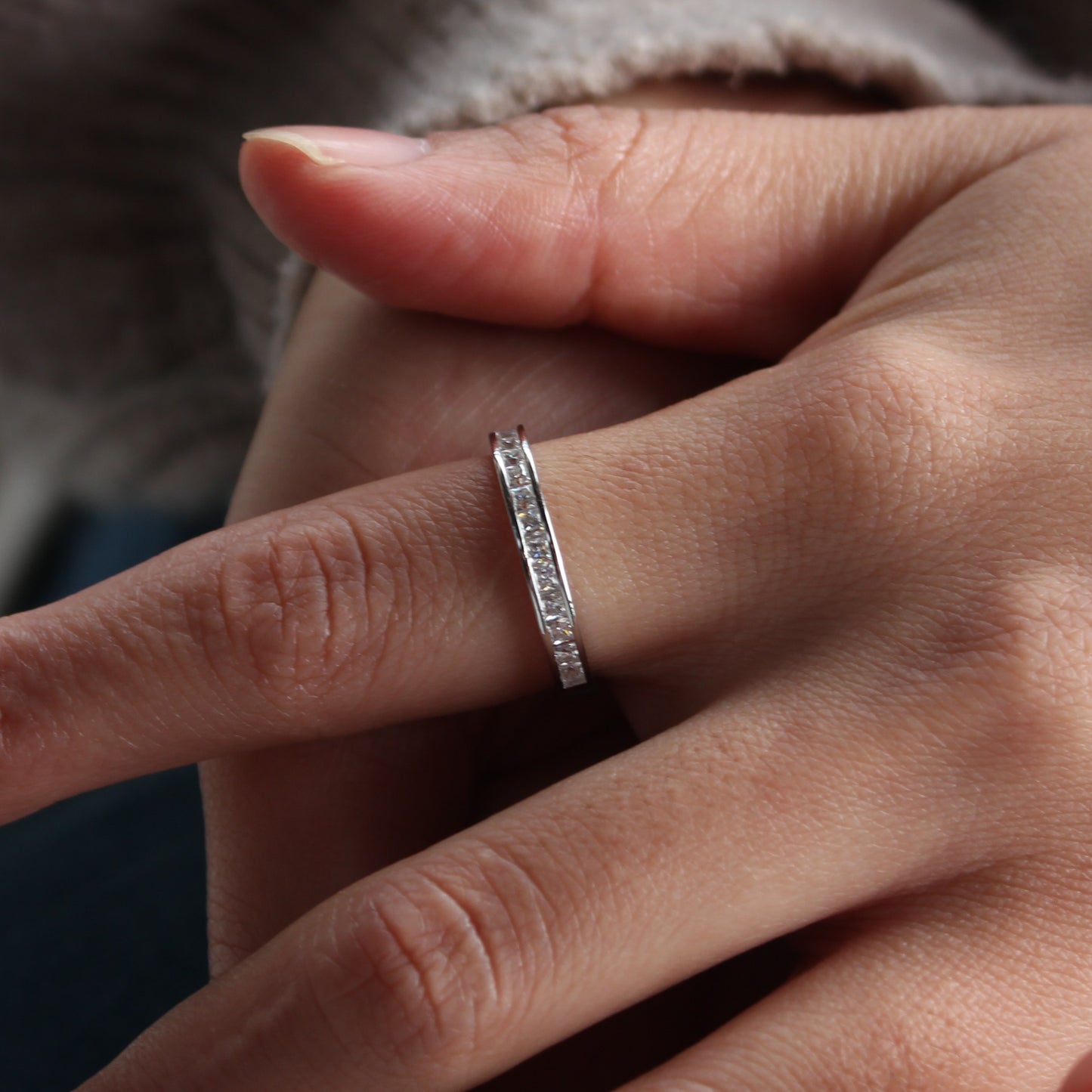Minimalist channel moissanite band ring worn on hand, white gold tone aesthetic
