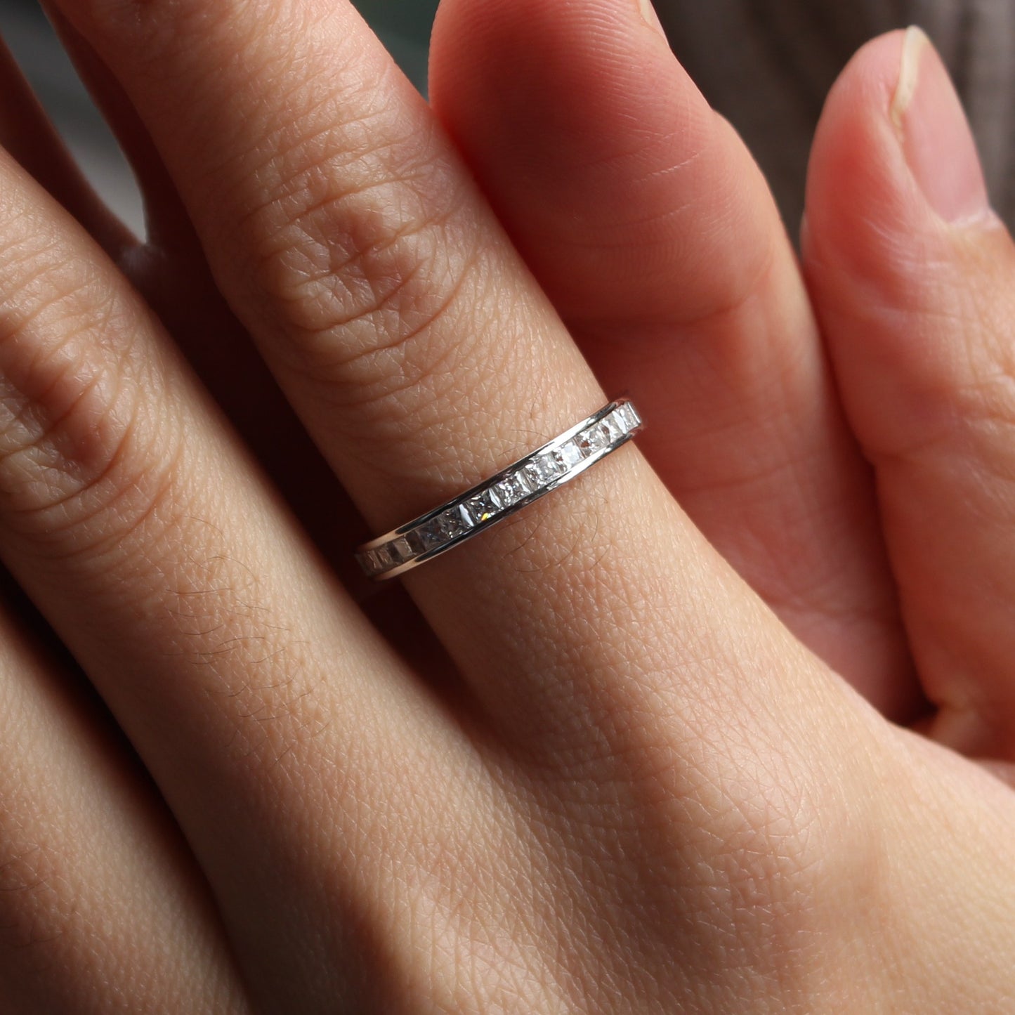 Baguette channel moissanite ring in white gold tone worn on hand, minimalist band style