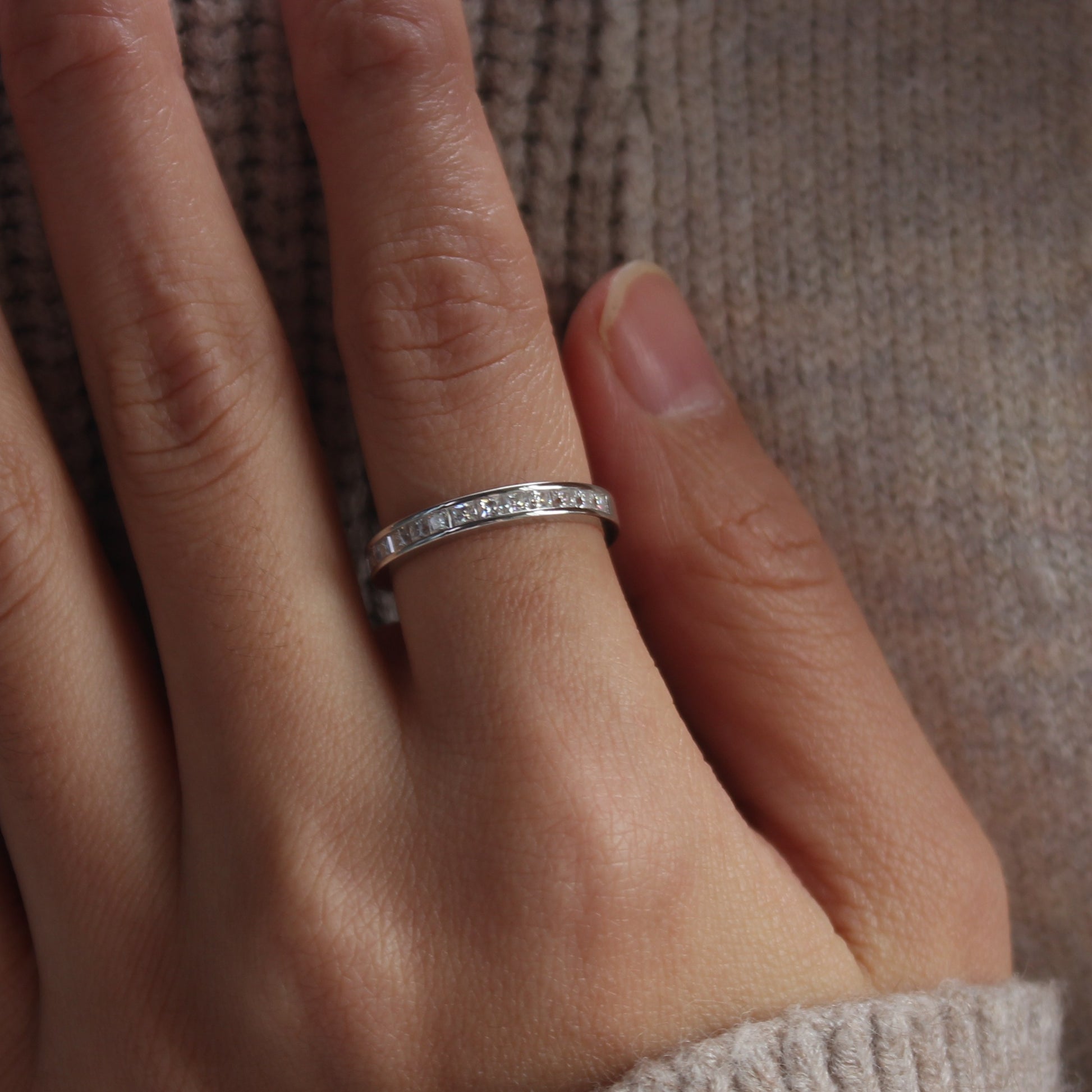 Channel set baguette moissanite band ring on hand, white gold tone with subtle sparkle