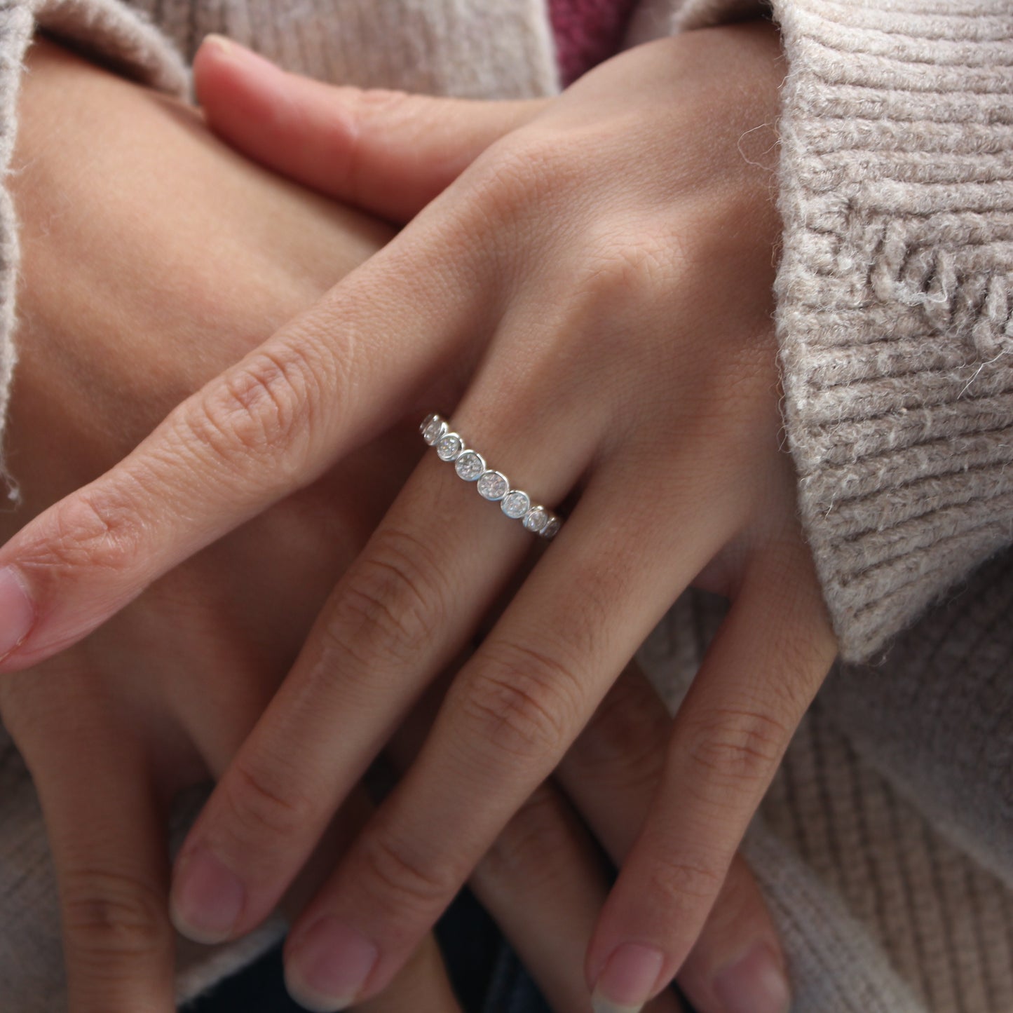 Minimalist bezel moissanite band worn on finger, white gold tone finish