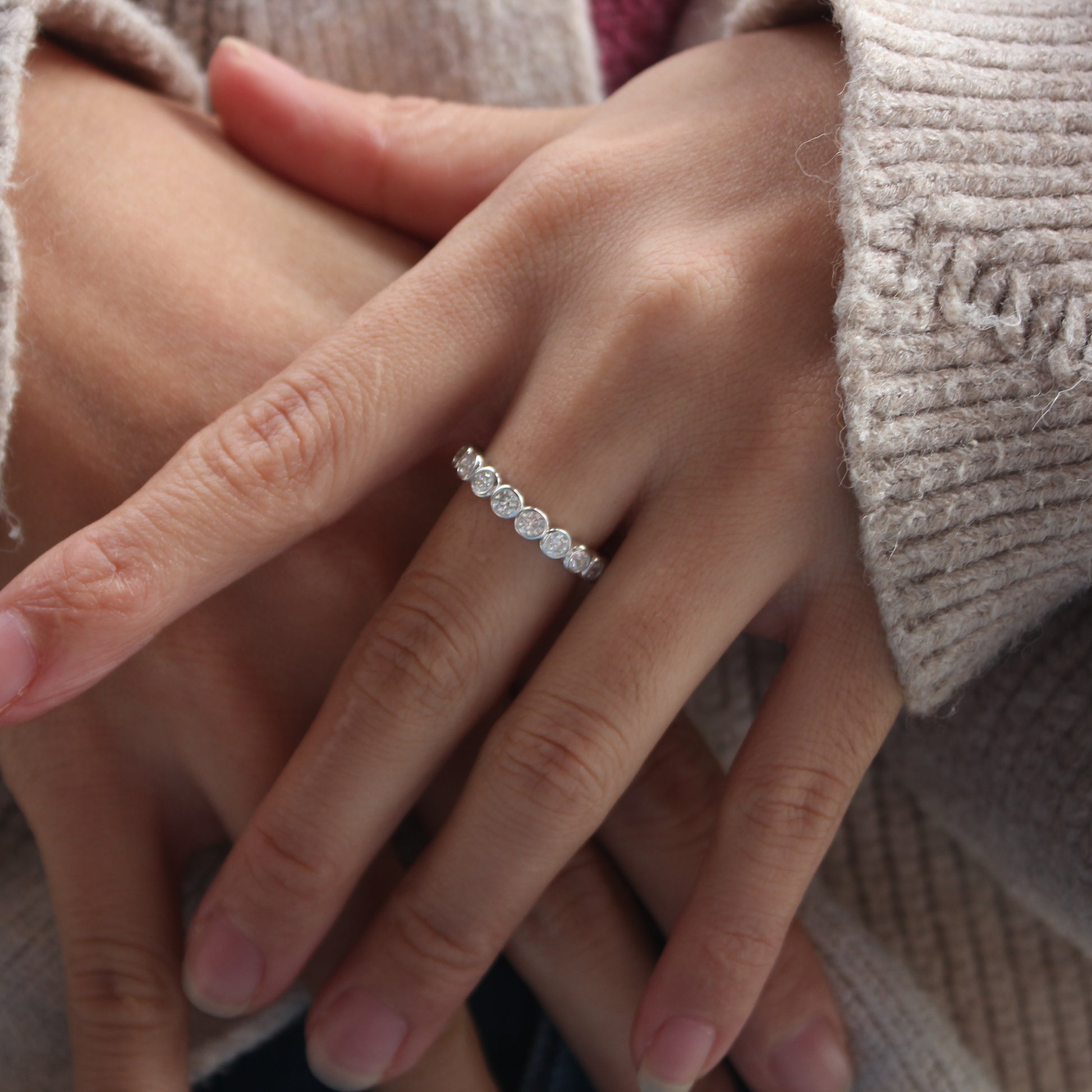 Minimalist bezel moissanite band worn on finger, white gold tone finish