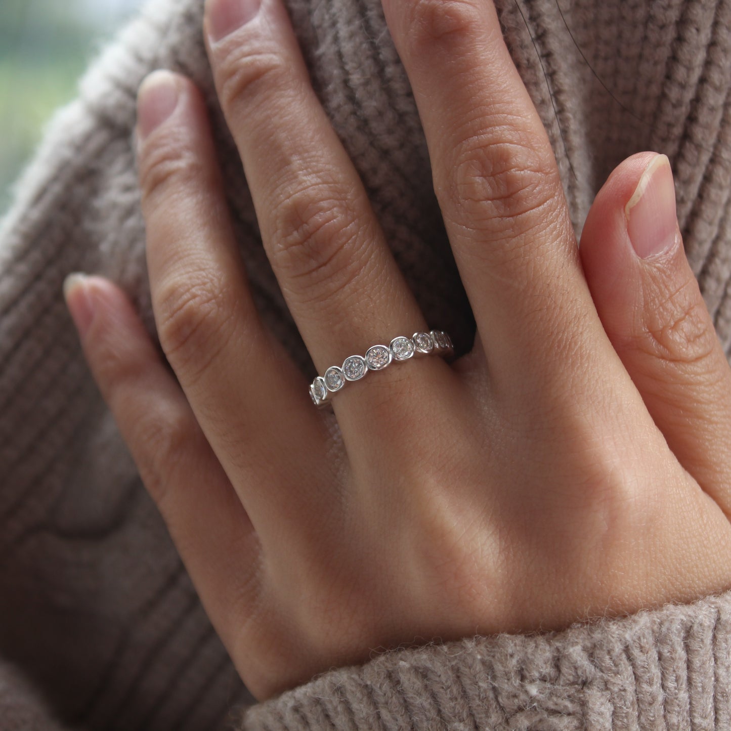Bezel eternity moissanite ring in white gold tone worn on hand, minimalist everyday style