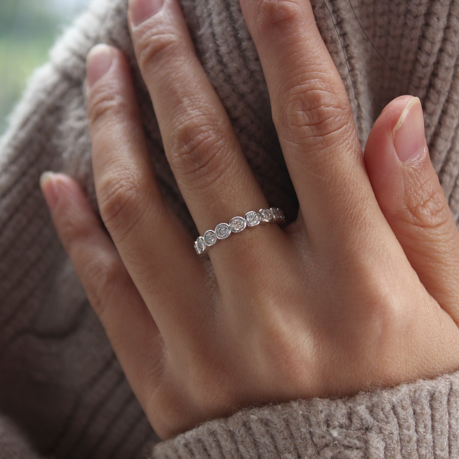 Bezel eternity moissanite ring in white gold tone worn on hand, minimalist everyday style