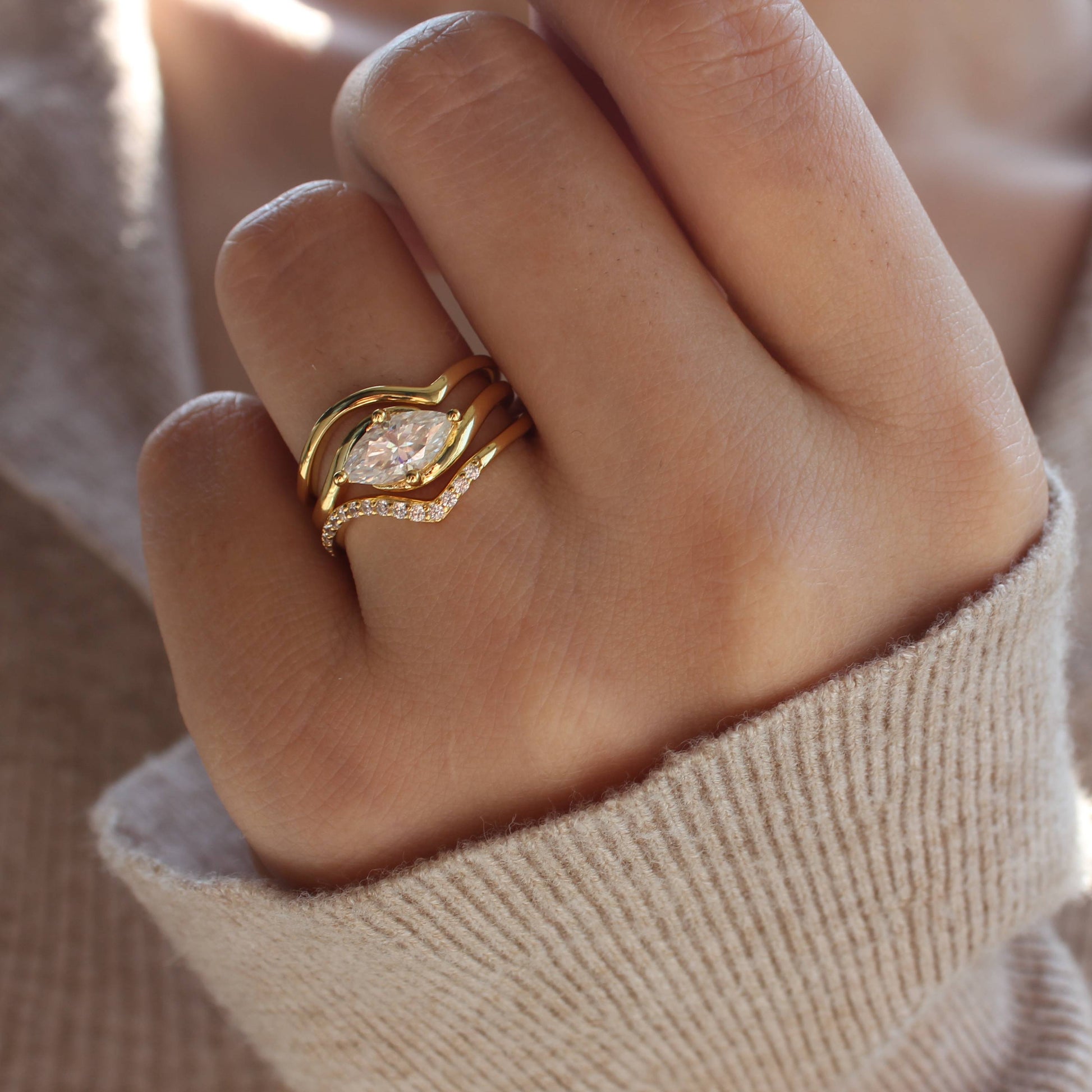 Curved moissanite stacking rings worn on hand, warm natural light