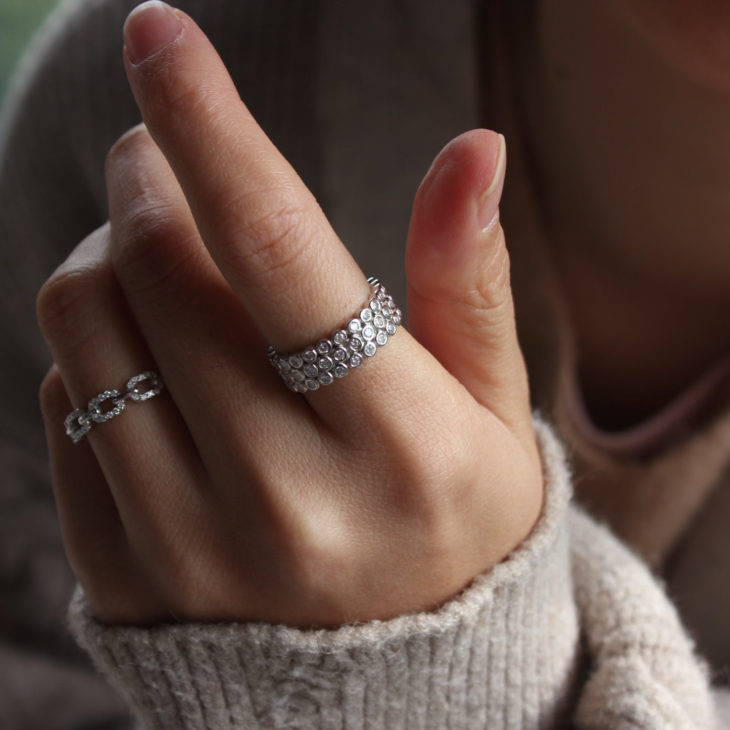 Close-up of dome pavé moissanite ring worn on finger, brilliant sparkle detail