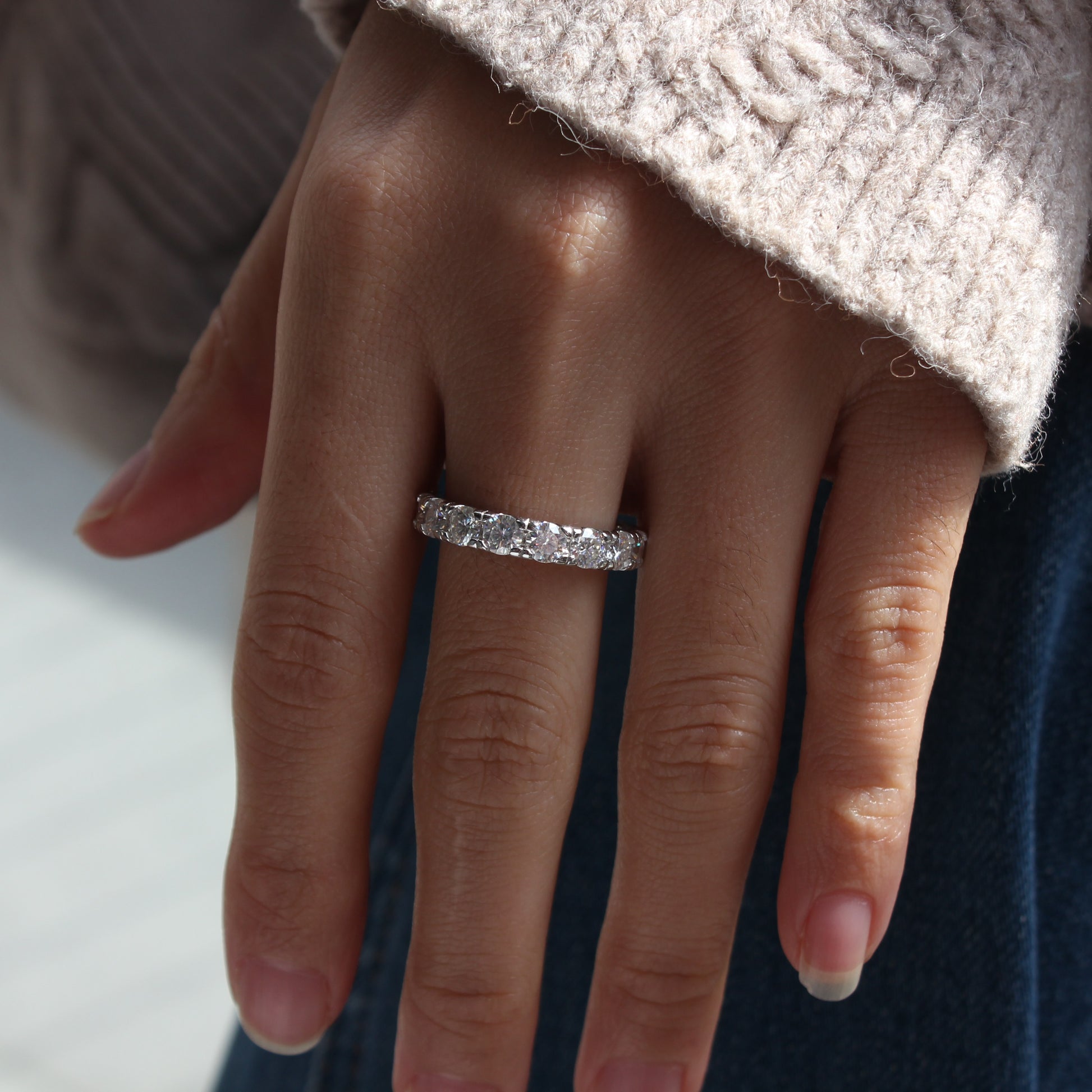 Woman wearing Elara moissanite eternity band ring in white gold tone, subtle sparkle on hand