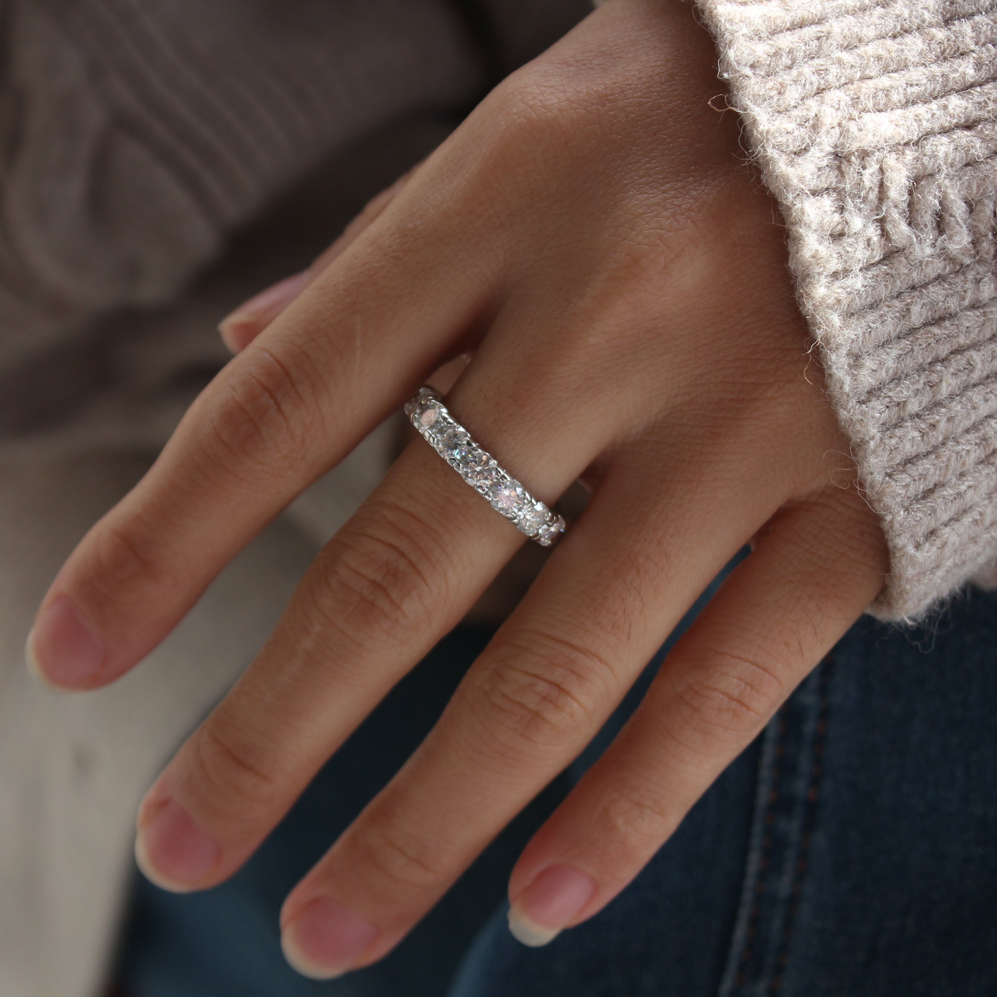 Elegant white gold tone moissanite eternity band worn in natural daylight