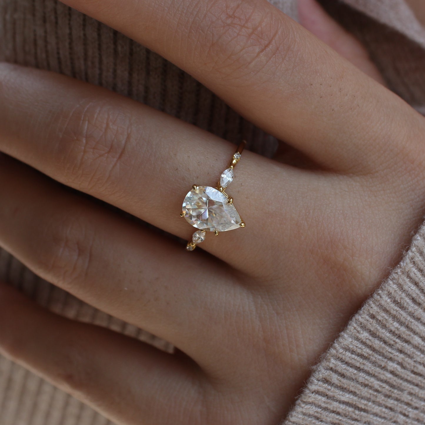Elara pear moissanite ring worn on finger close up