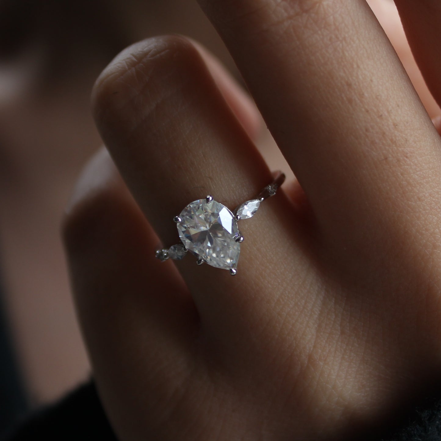 Elara pear moissanite ring worn on finger in low light