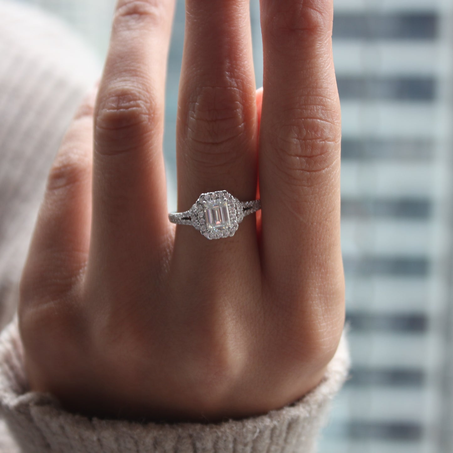 Emerald cut halo moissanite ring in white gold tone worn on hand, elegant style