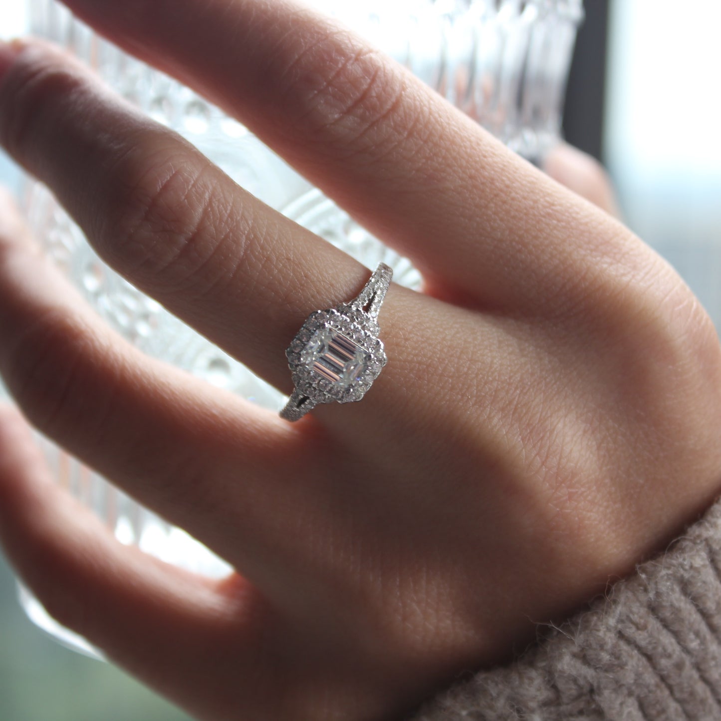 Elegant emerald cut moissanite ring worn on hand, white gold tone brilliance