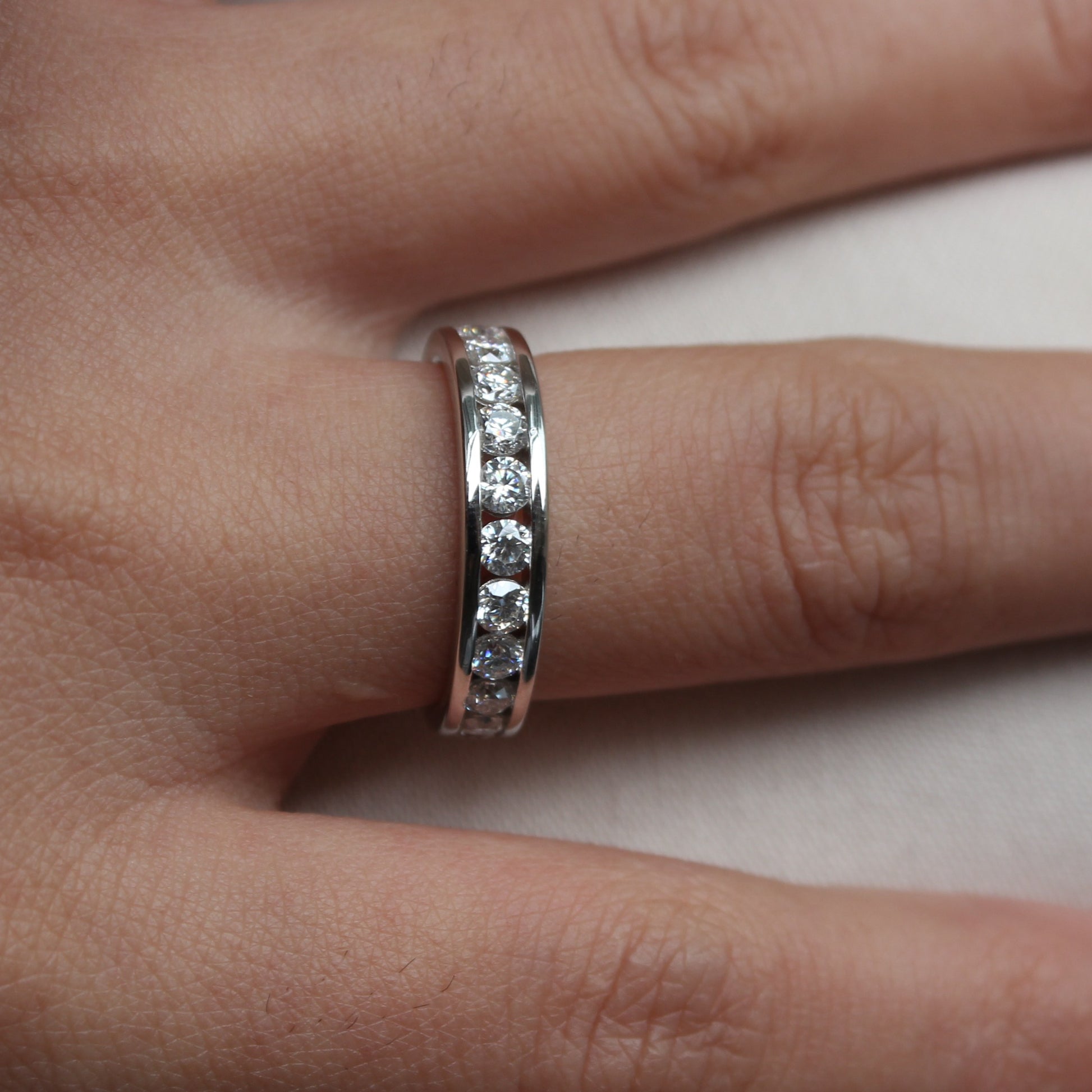 Woman wearing Liora moissanite band ring in white gold tone, delicate sparkle on hand