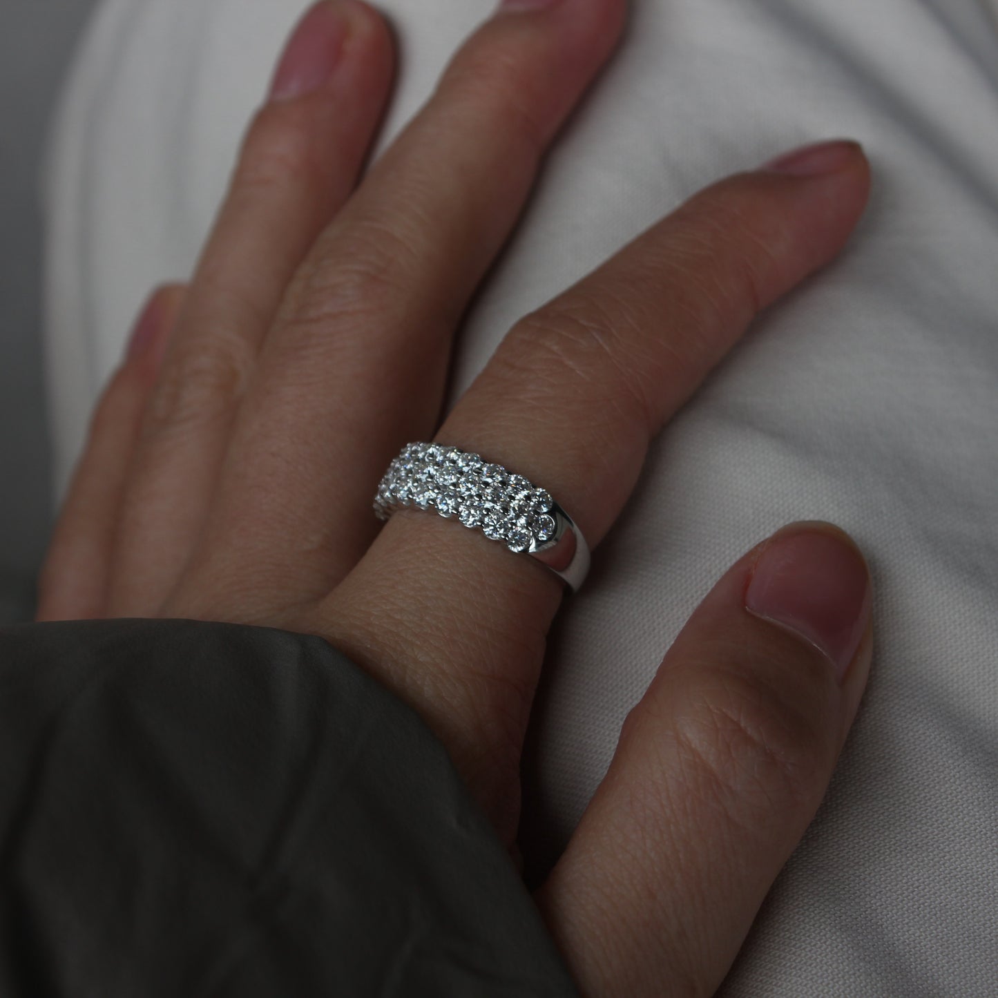 Wide pavé moissanite band ring on hand, white gold tone with full sparkle