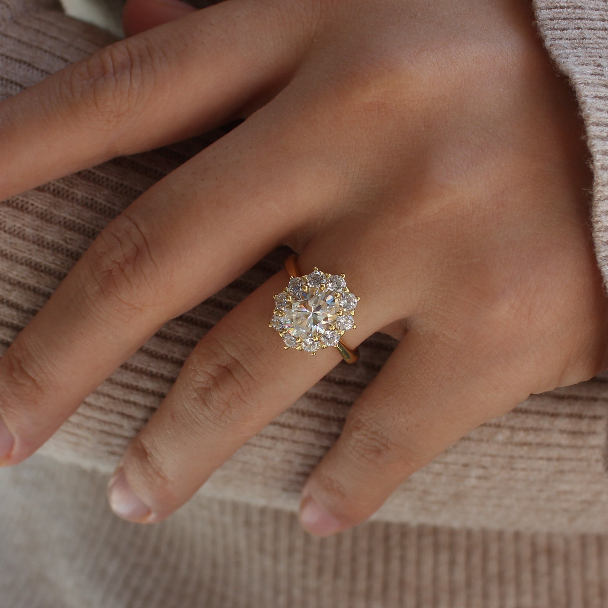 Oval moissanite halo ring worn on finger, soft natural light