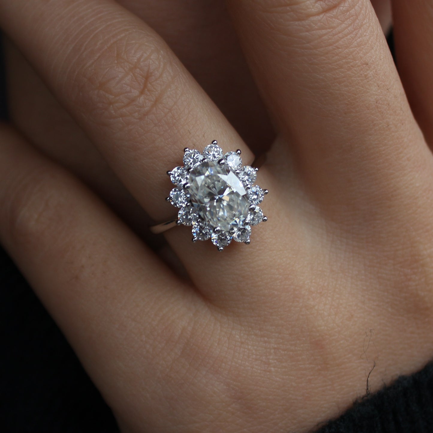 Oval halo moissanite ring close-up on finger, sparkling details