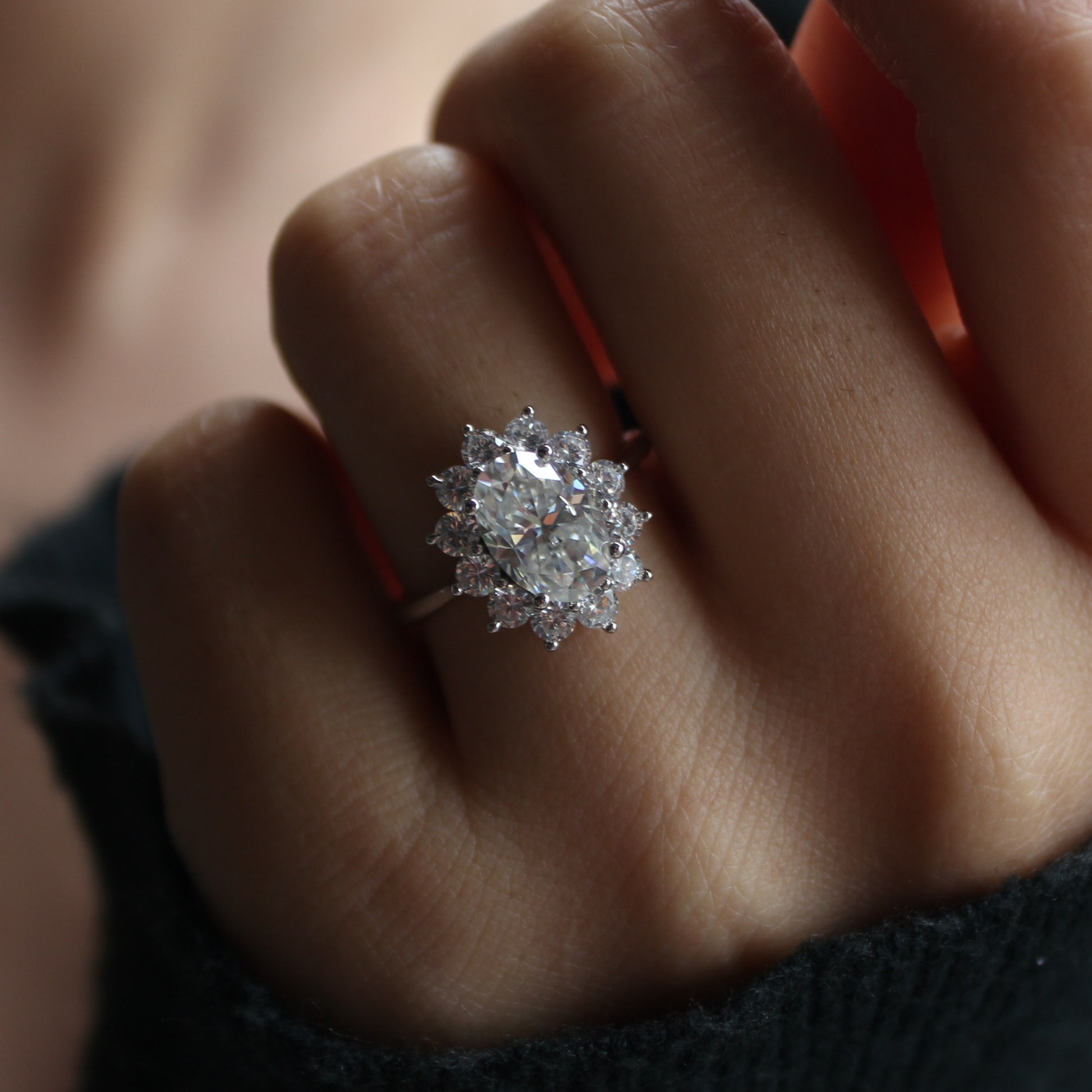 Oval moissanite halo ring worn on hand, soft warm lighting