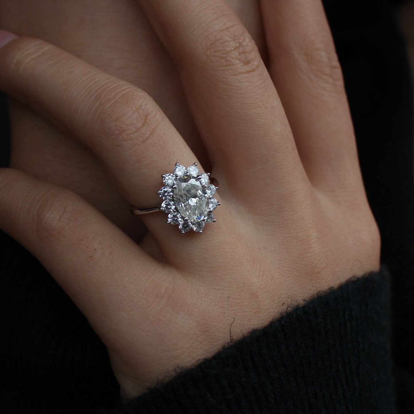 Oval halo moissanite ring worn on hand in white gold tone