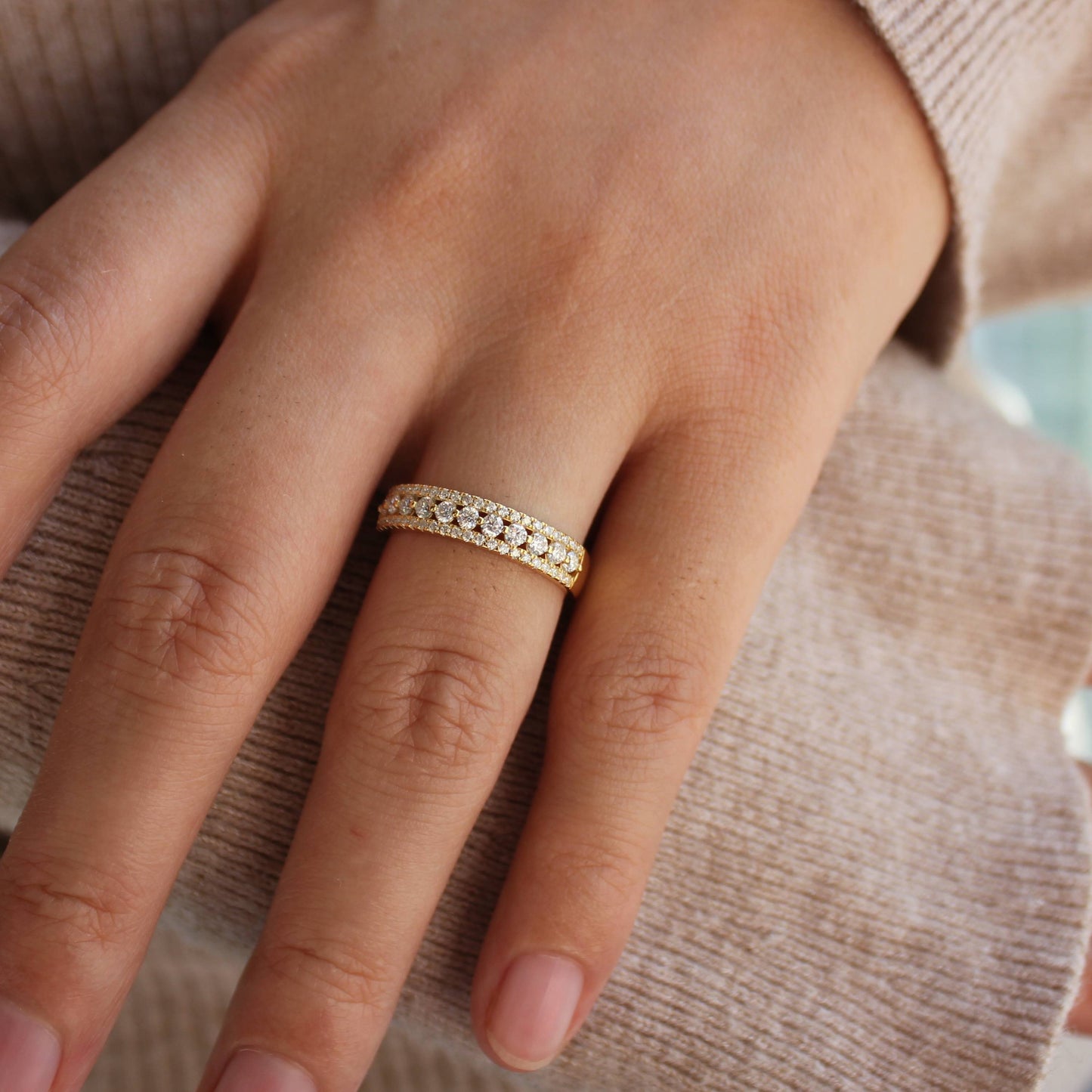 Close-up of triple pavé moissanite band styled with cozy knit sleeve